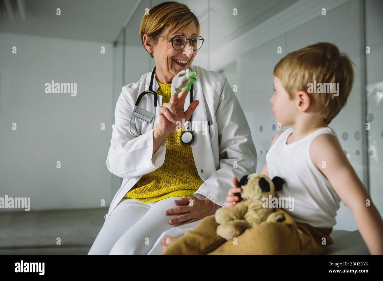 Peditricien avec des poupées de doigt et un tout-petit en pratique médicale Banque D'Images