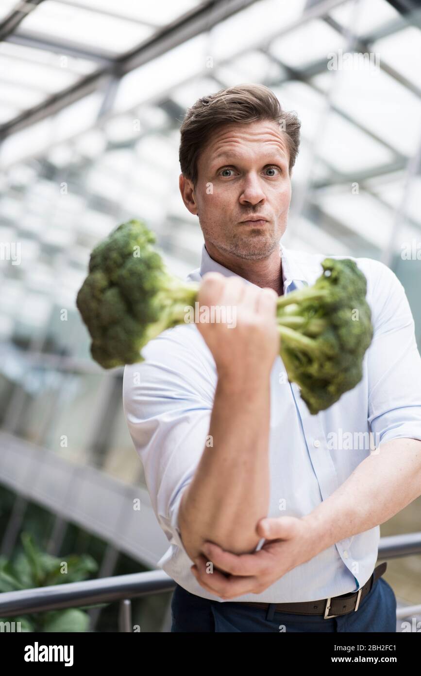Homme d'affaires faisant de l'entraînement de poids avec brocoli Banque D'Images