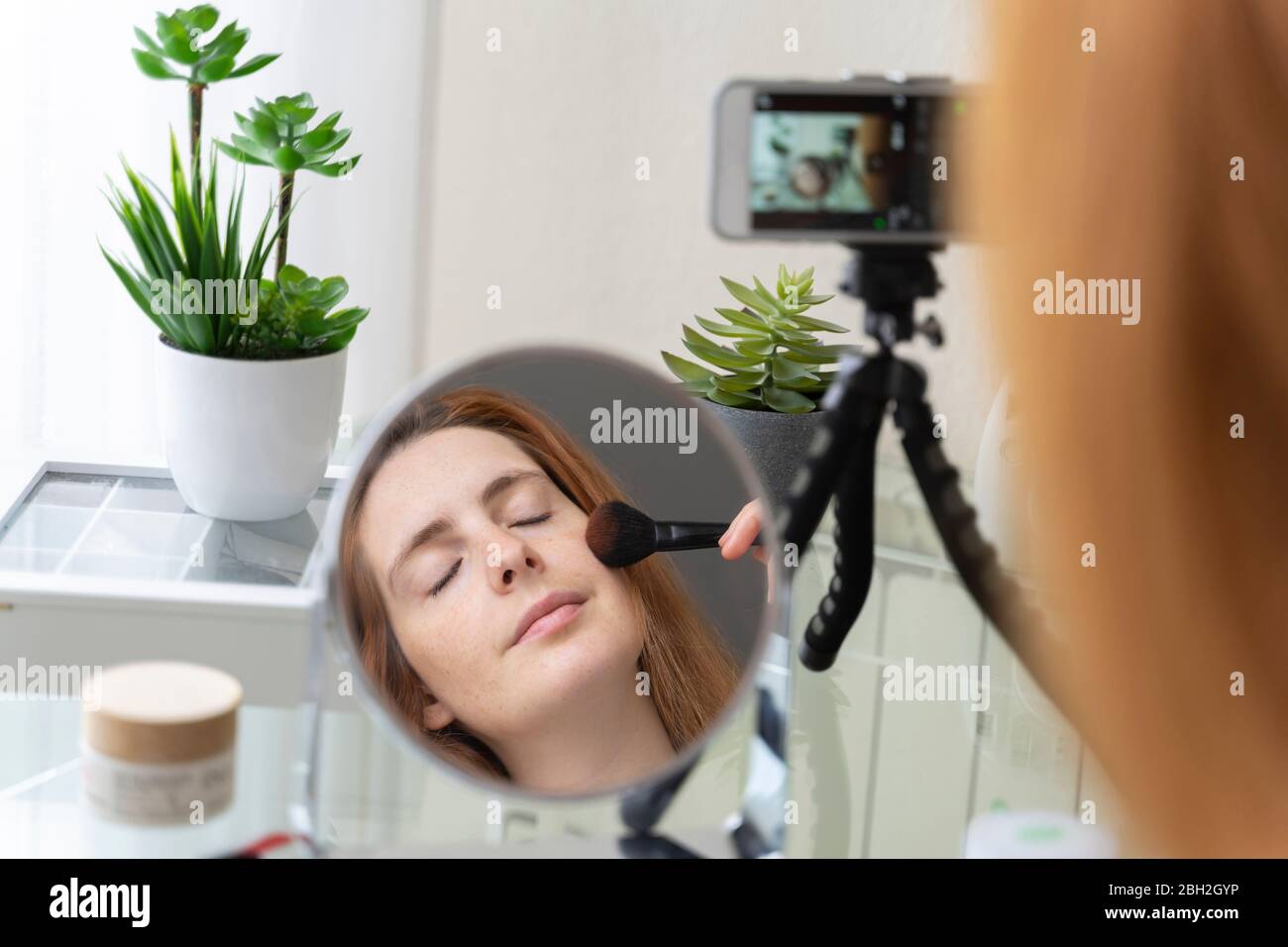 Jeune femme filmant sa routine de beauté à la maison Banque D'Images