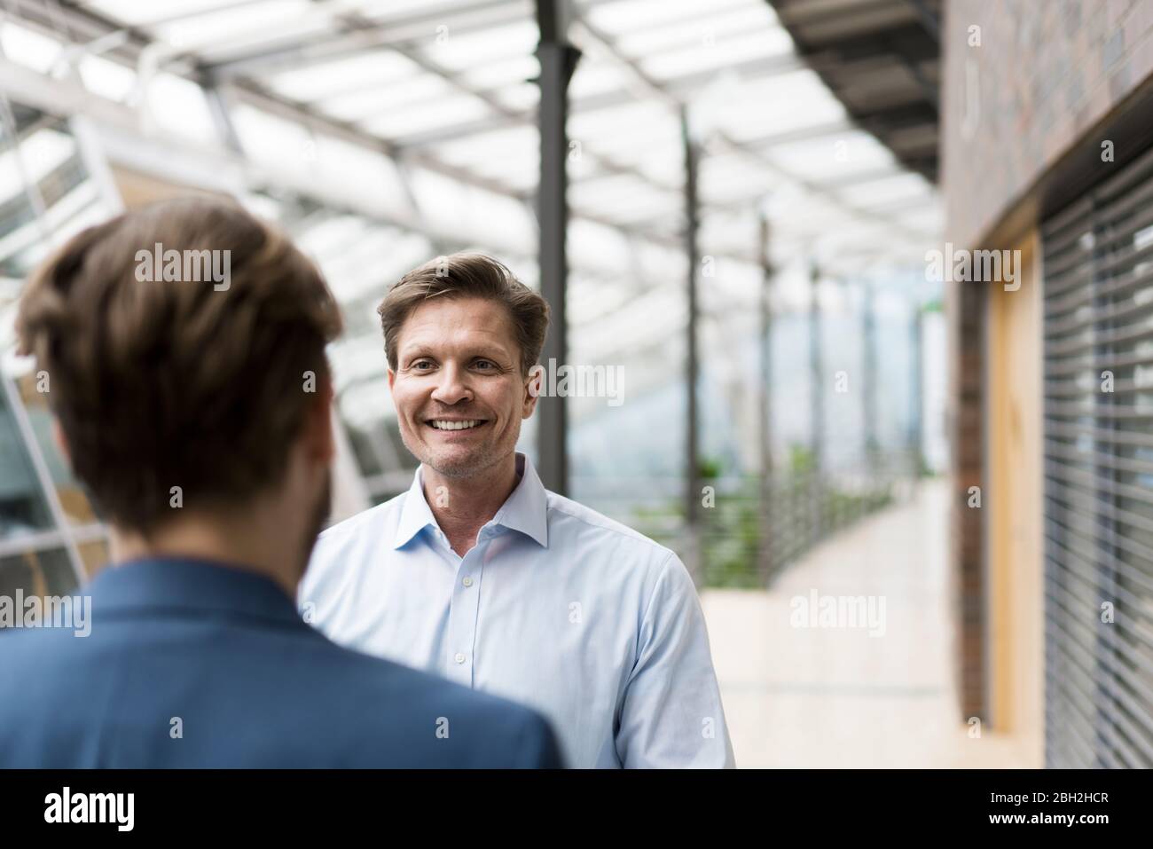 Homme d'affaires parlant à un collègue dans l'atrium du bâtiment de bureau Banque D'Images