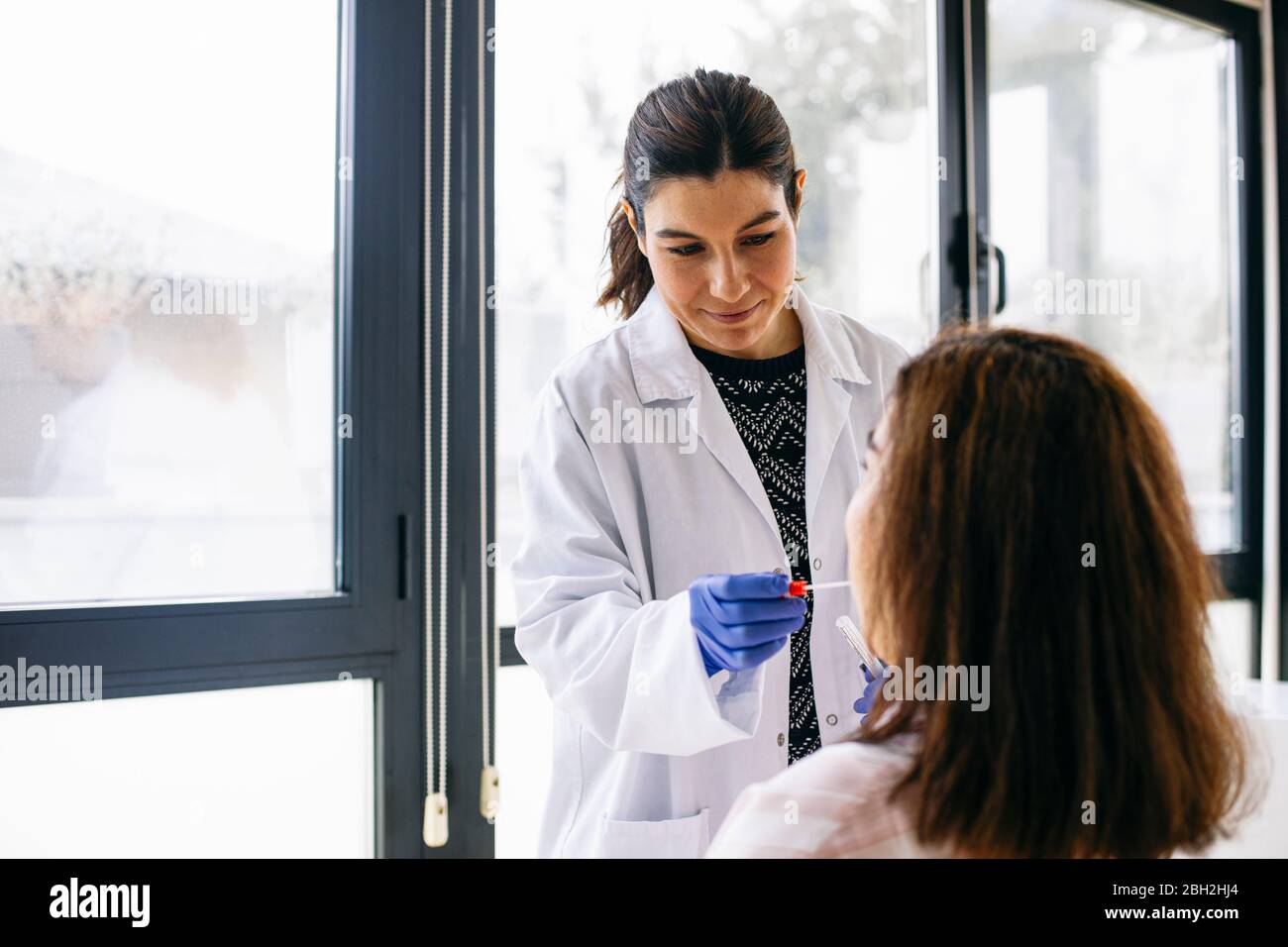 Médecin prenant un écouvillon de la bouche du patient Banque D'Images