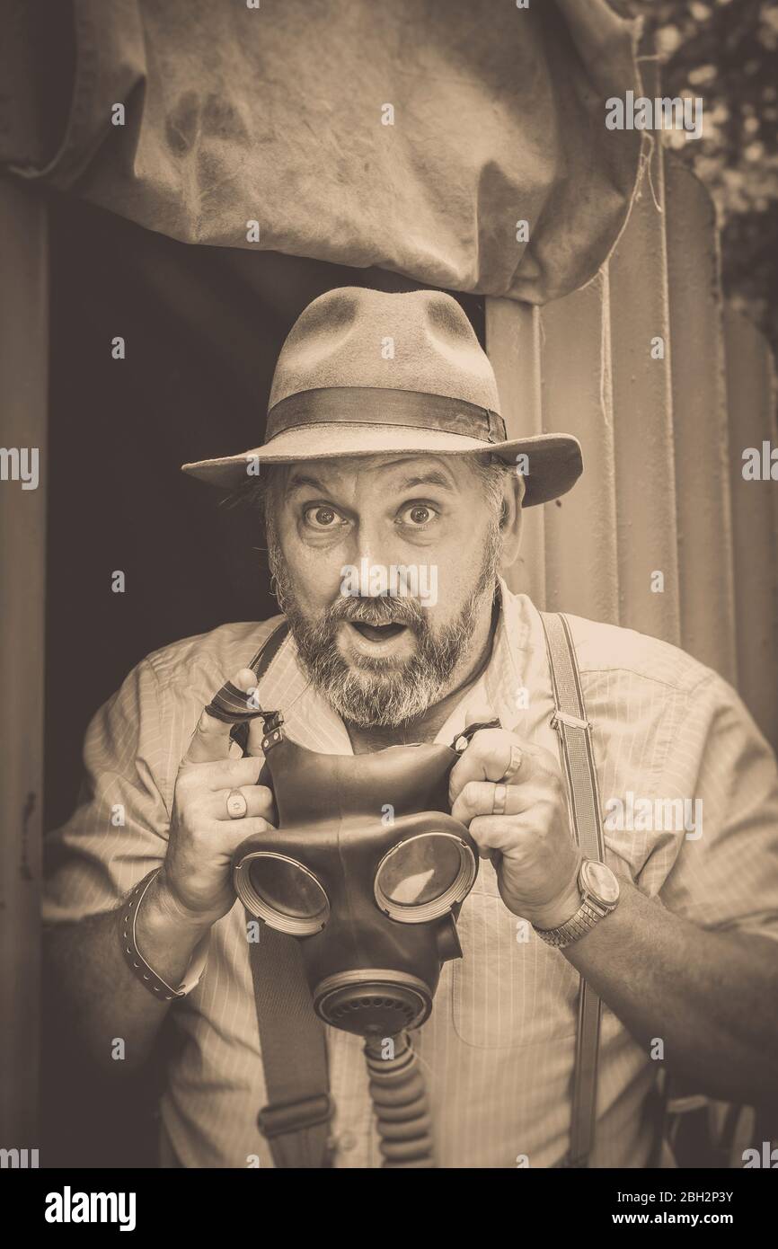 Portrait avant sépia vintage, homme des années 1940 avec masque à gaz isolé à l'extérieur à Anderson Shelter, Black Country Museum 1940 événement d'été de guerre de la seconde Guerre mondiale, Royaume-Uni. Banque D'Images