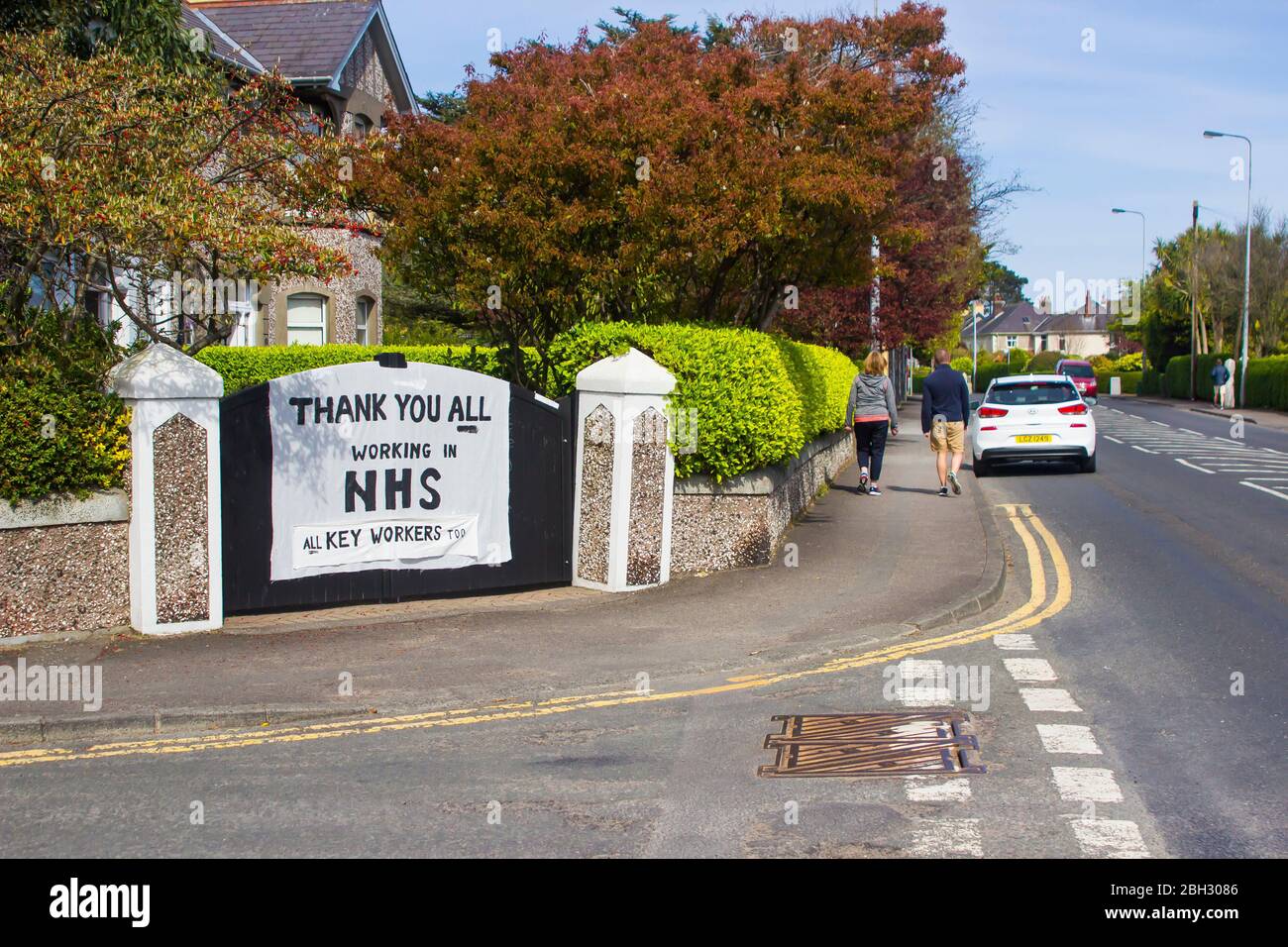 22 avril 2010 Groomsport Road, Bangor, Irlande du Nord. Un homme et une femme qui marchont devant une main message écrit de soutien pour le Service national de santé Banque D'Images