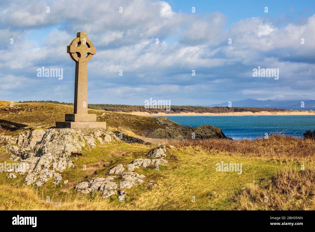 La croix celtique sur l'île de Llanddwyn avec Snowdonia en arrière-plan, Anglesey Banque D'Images
