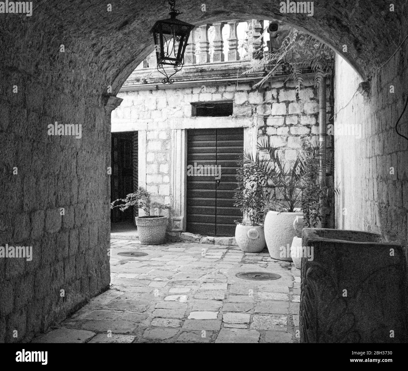Image en noir et blanc de l'arcade menant à la cour et aux maisons pavées, la vieille ville, Kotor, site classé au patrimoine mondial de l'UNESCO, Monténégro, Europe Banque D'Images