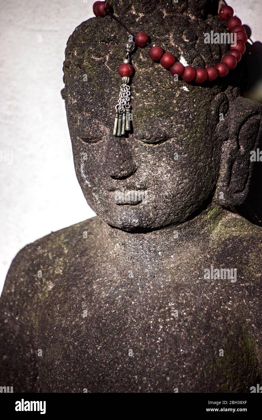statue de bouddha en pierre avec perles de prière rouges Banque D'Images
