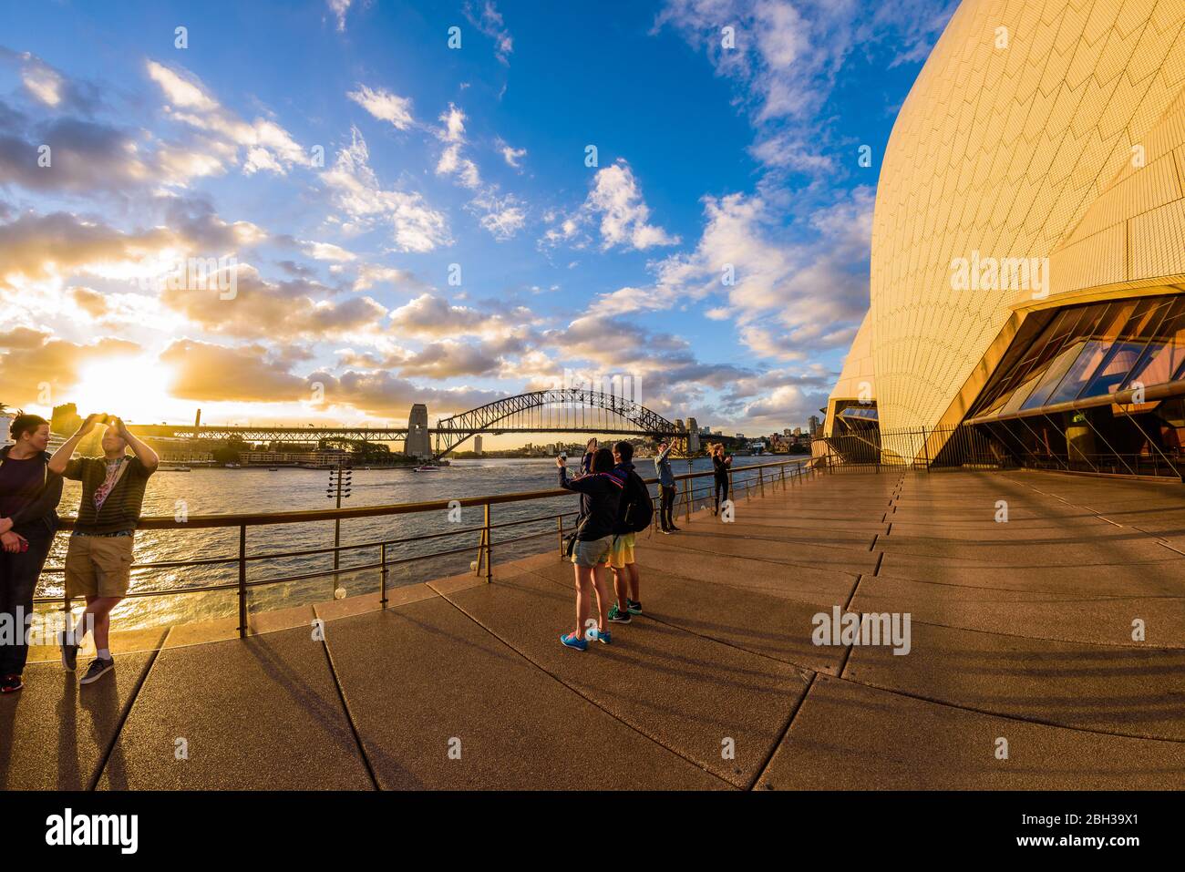 Sydney, Australie. Les touristes et les habitants de la région apprécient le coucher du soleil lors d'une chaude soirée d'été près de l'Opéra. Dans le contexte le pont du port. Banque D'Images