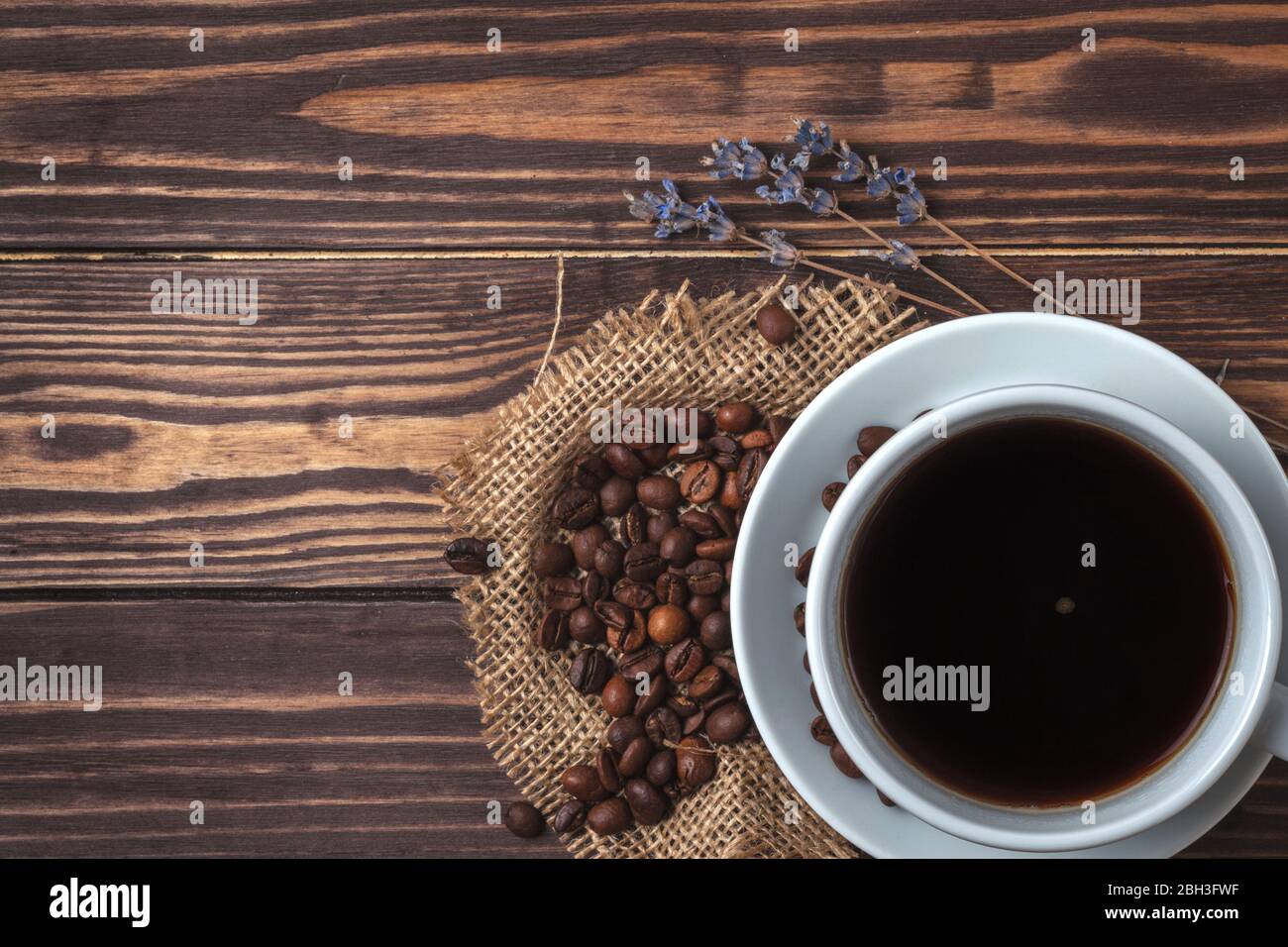 Tasse avec café noir, grains de café et branches de lavande sur un plan d'examen en bois. Vue de dessus. Banque D'Images