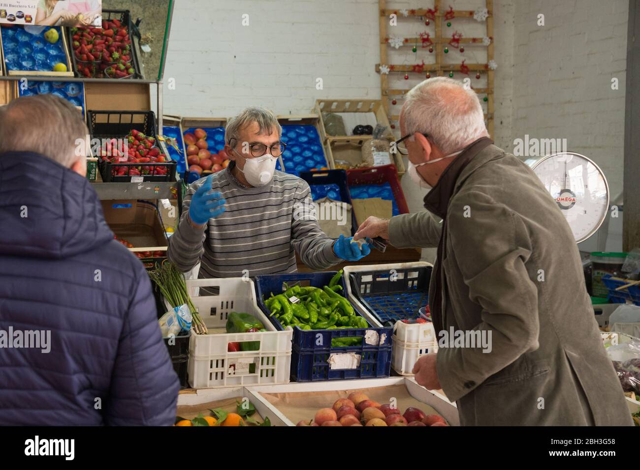 Campobasso,région de Molise,Italie:un vendeur de fruits et légumes sert des clients à son comptoir pendant l'urgence du coronavirus en Italie. Banque D'Images