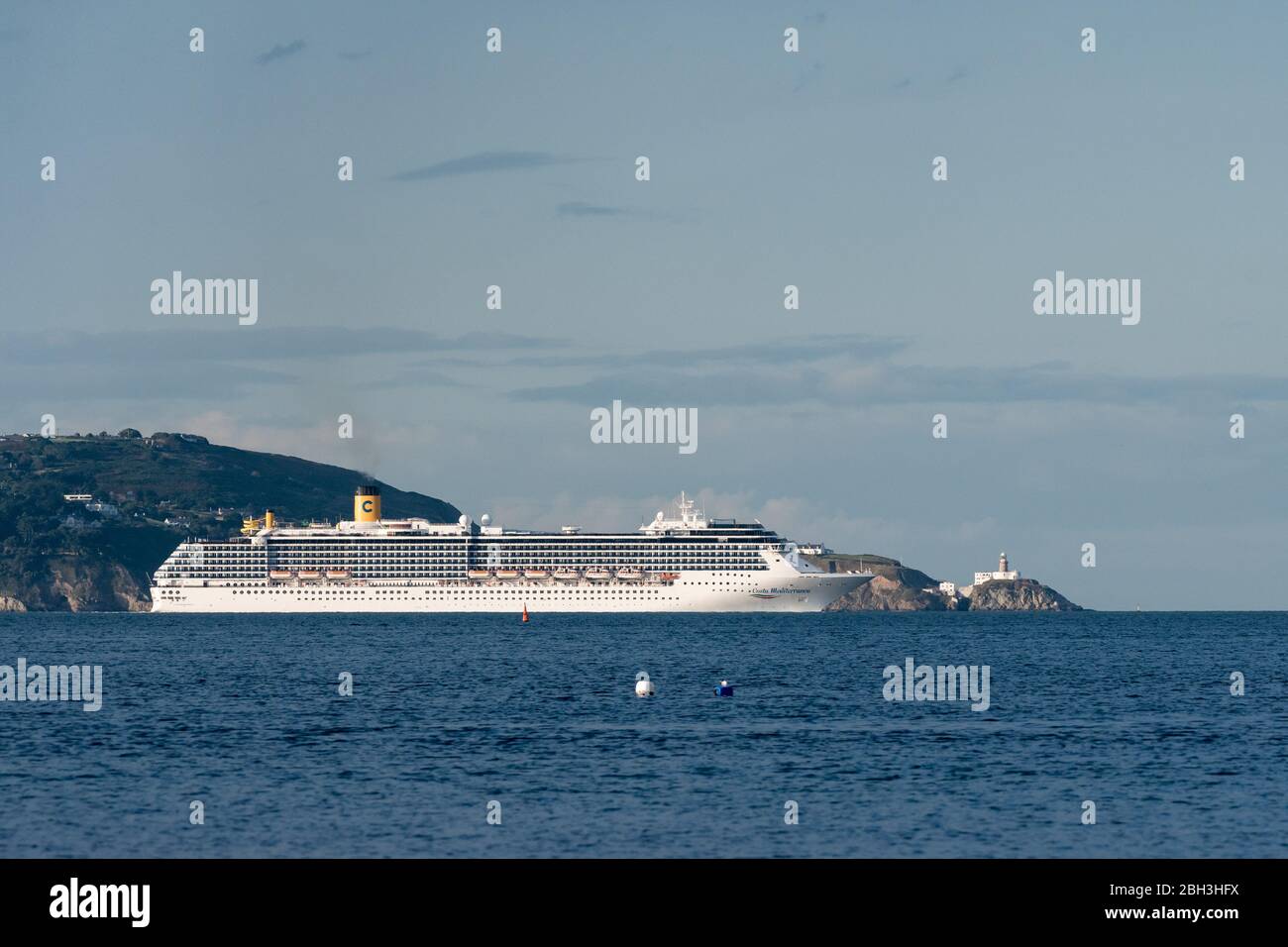 Costa Mediterranea bateau de croisière à la sortie de la baie de Dublin, une journée ensoleillée avec Howth Head et le phare Bailey en arrière-plan. Banque D'Images