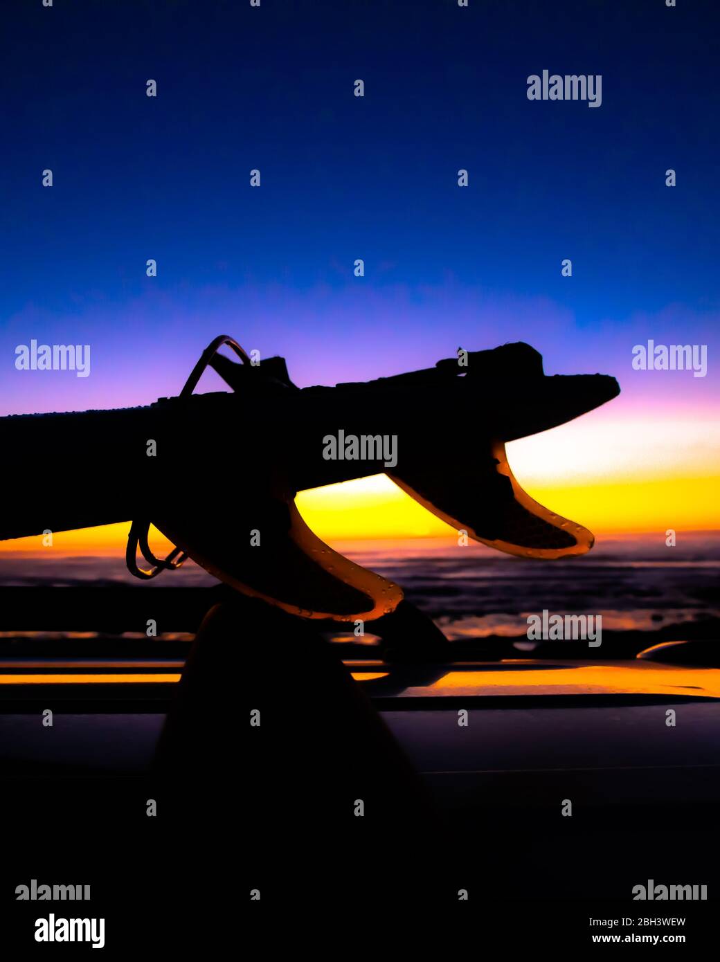 Silhouette de planche de surf avec ailerons sur un véhicule au coucher du soleil Banque D'Images