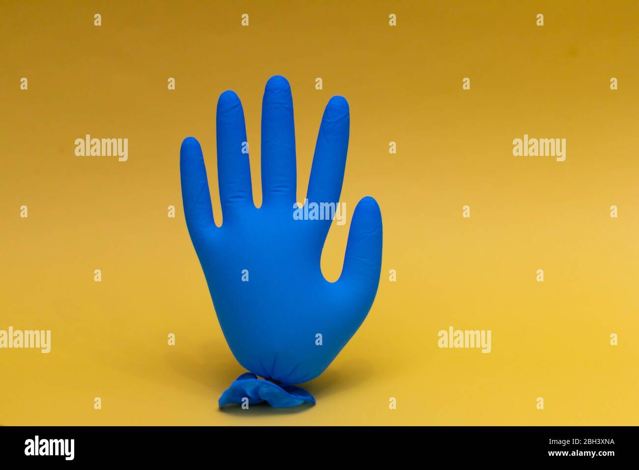 Gant médical bleu gonflé. Sur fond jaune avec espace de copie. Banque D'Images