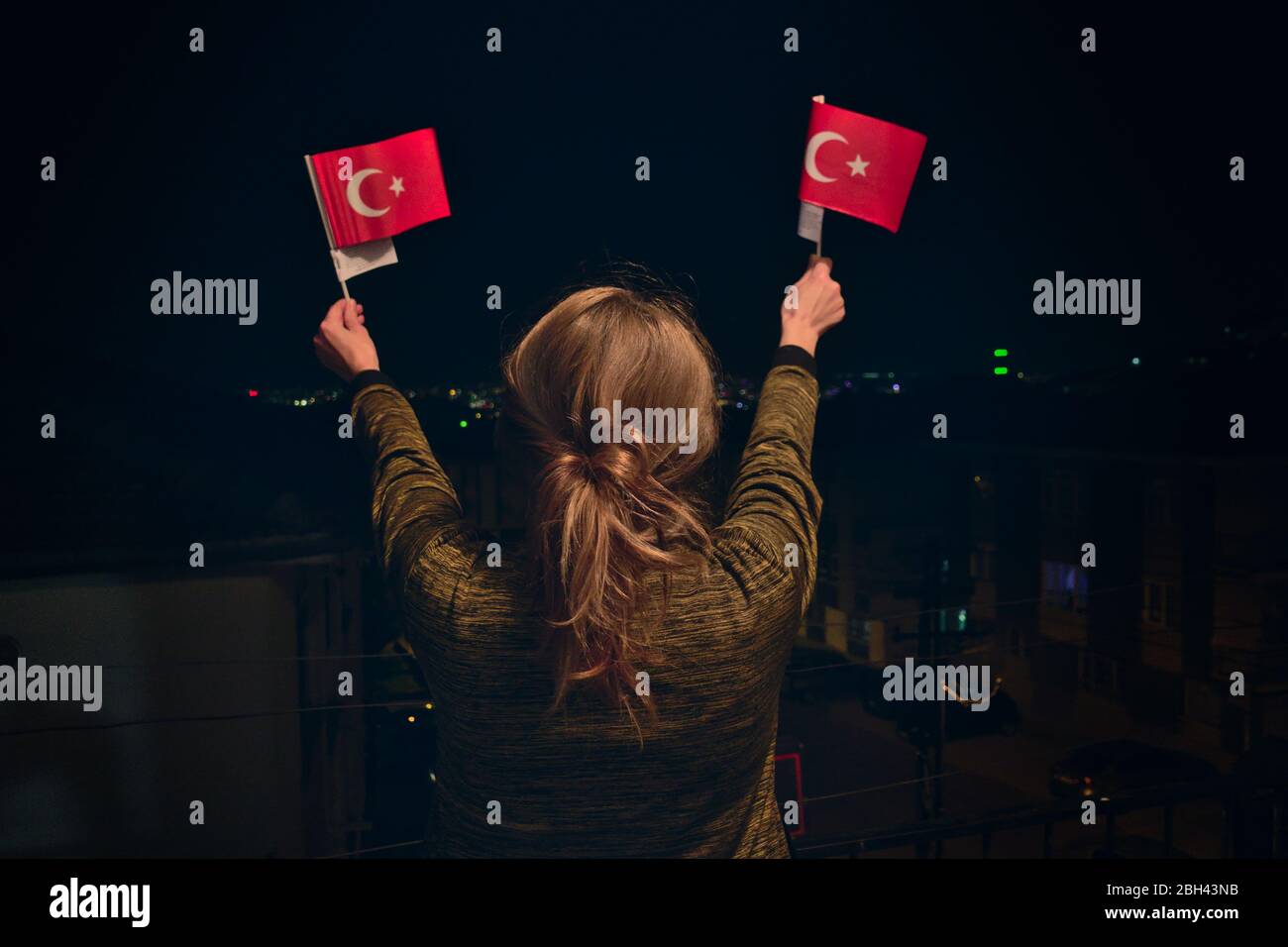 La Femme turque Holding, agitant 2 drapeaux turcs la nuit célébrant le 23 avril souveraineté nationale Journée de l'enfant Banque D'Images