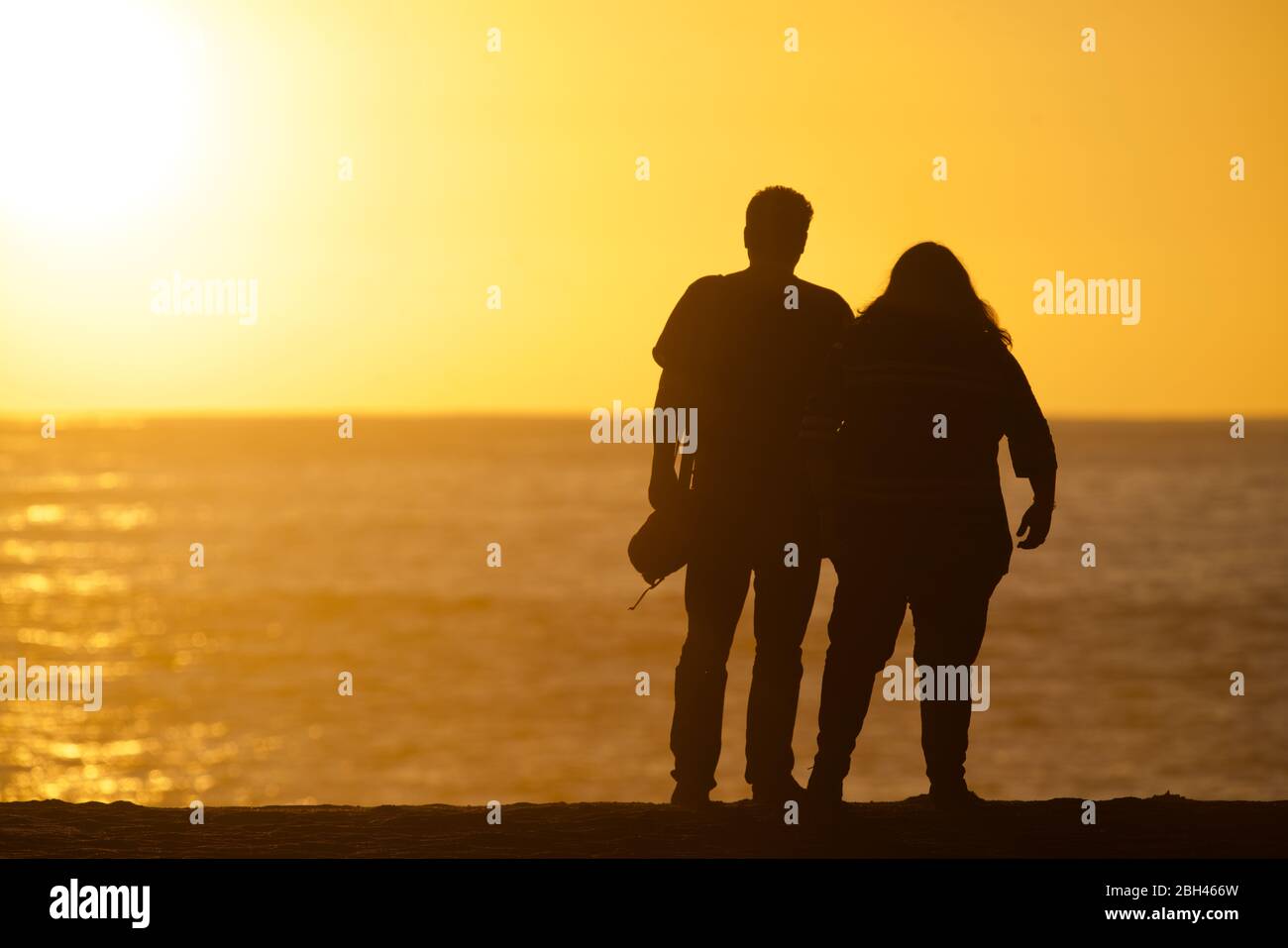 Couple regardant le coucher du soleil sur l'océan Banque D'Images