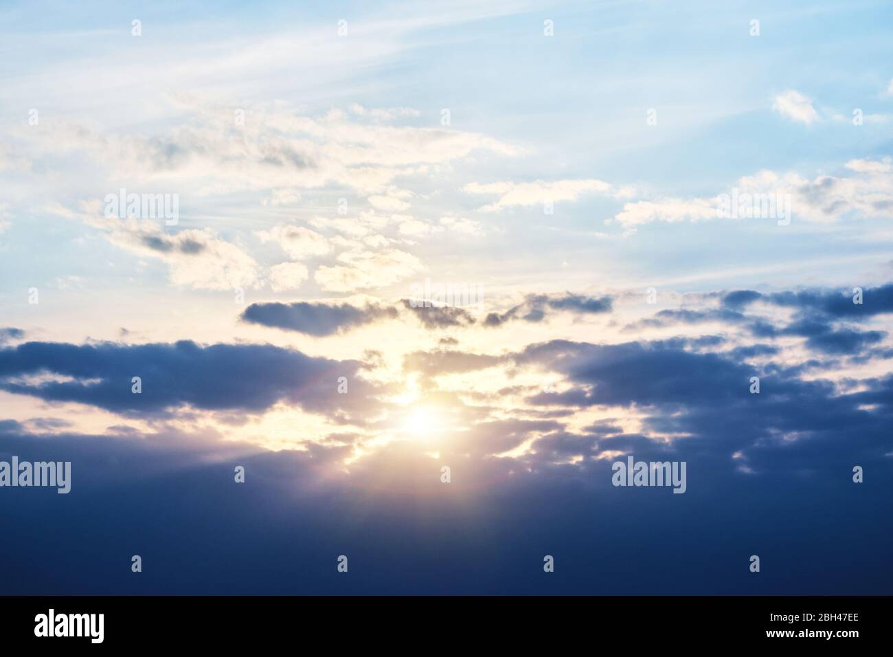 Le soleil se couche derrière les nuages et les rayons de lumière traversent les nuages Banque D'Images