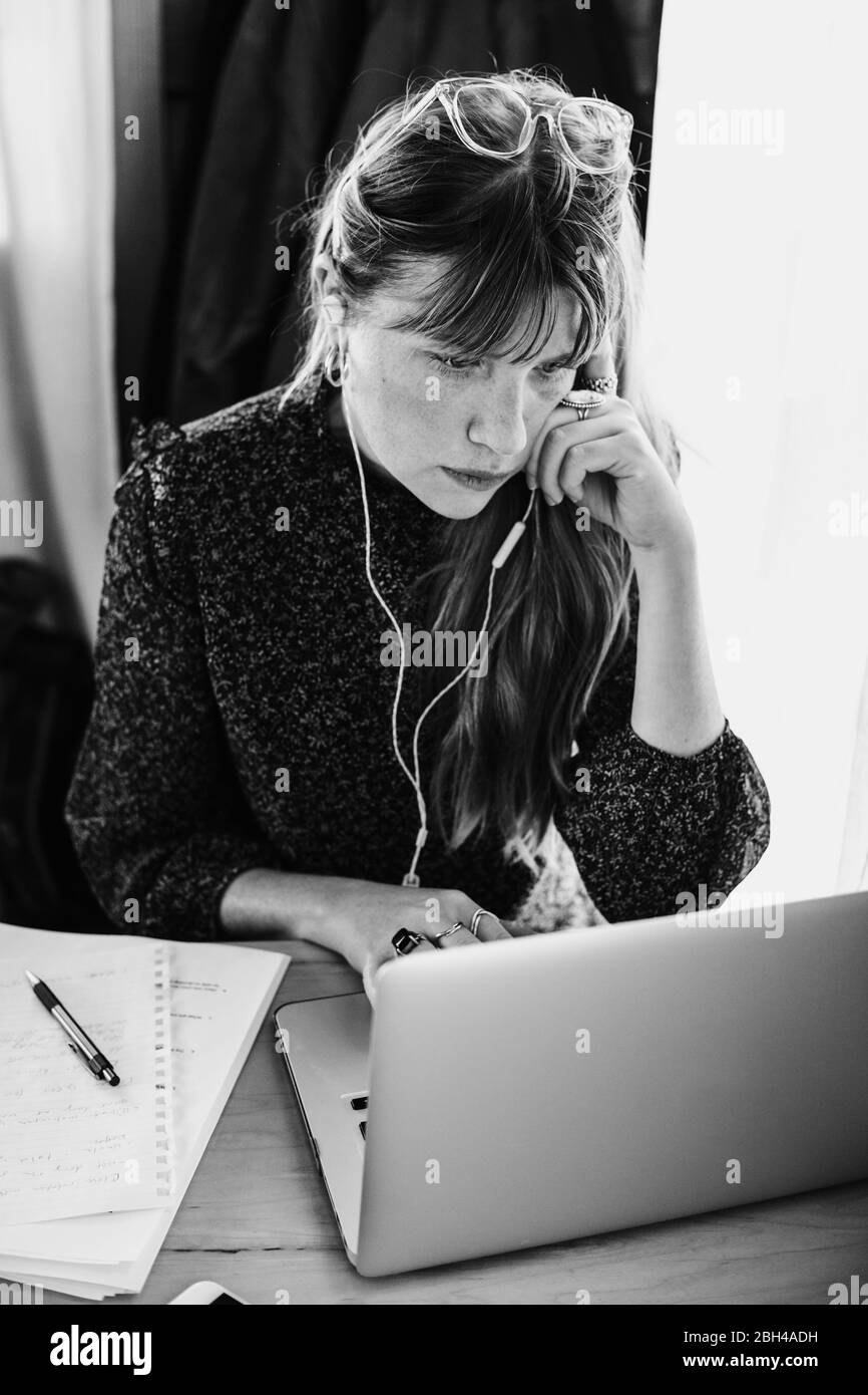 Femme d'affaires travaillant sur un ordinateur portable prenant des notes et de gérer son entreprise de la maison pendant le covid-19 rester à la maison de commande, image noir et blanc Banque D'Images
