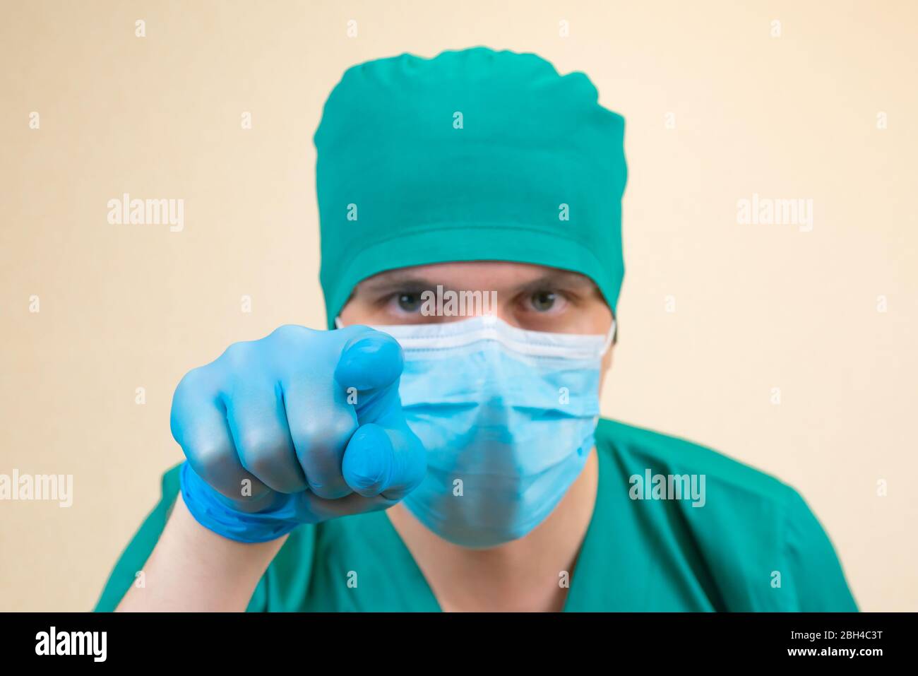 Le médecin portant des gants bleus de protection verts et un masque bleu pointe tout droit. Banque D'Images