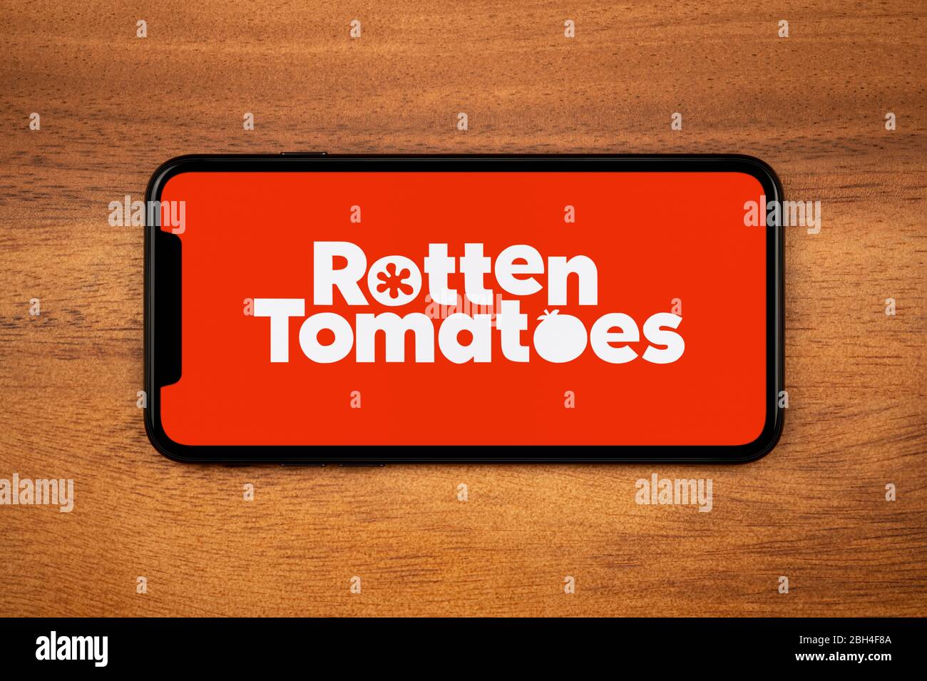 Un smartphone affichant le logo Rotten Tomatoes repose sur une table en bois ordinaire (usage éditorial uniquement). Banque D'Images