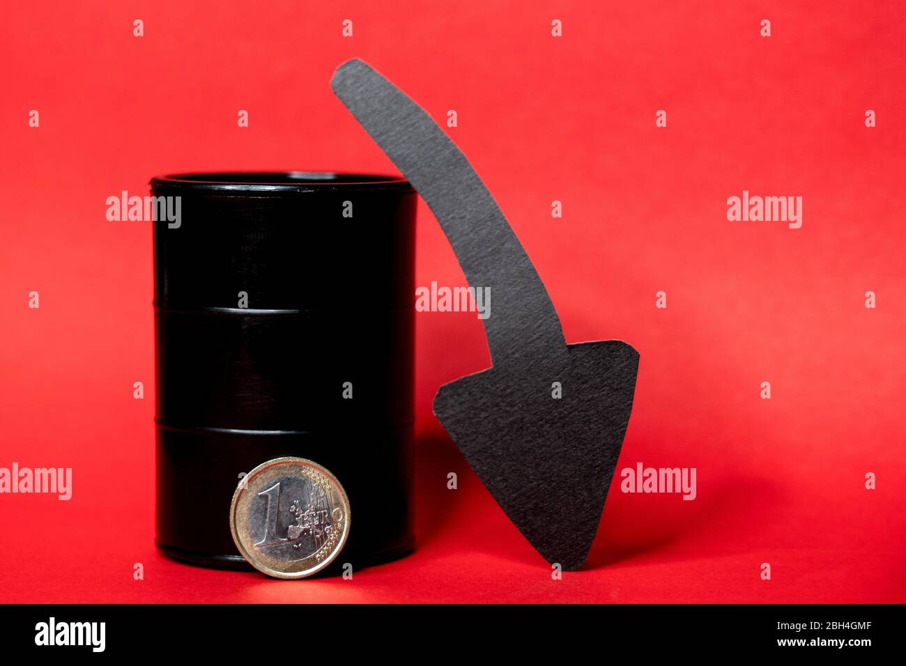 Baril de pétrole noir avec une pièce de monnaie d'un euro et une flèche vers le bas sur un fond rouge. Le prix du baril de pétrole chute dans le tableau. Tendance du marché pétrolier. Infographie sur le pétrole. Banque D'Images