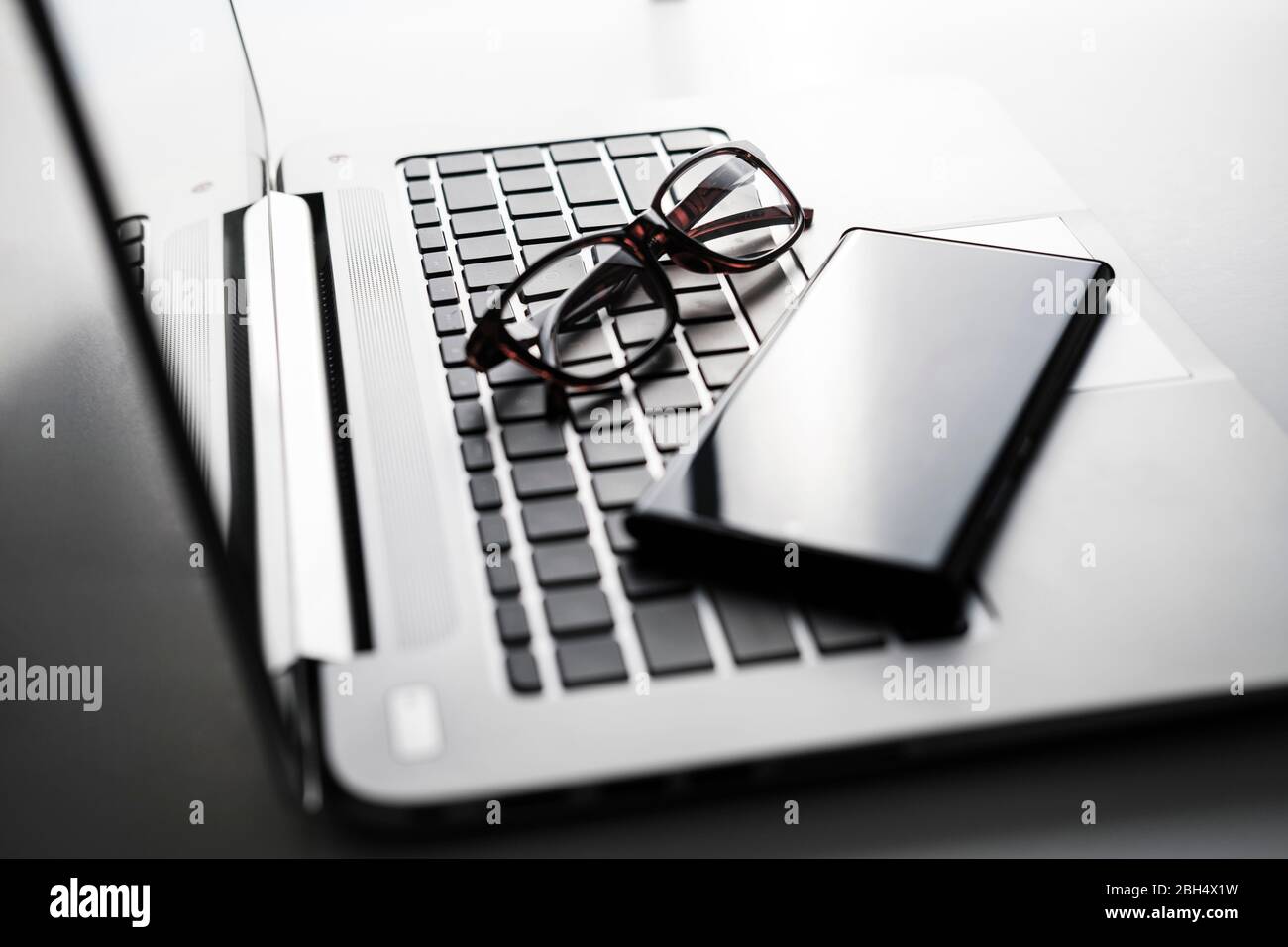 Smartphone et lunettes sur le clavier de l'ordinateur portable Banque D'Images