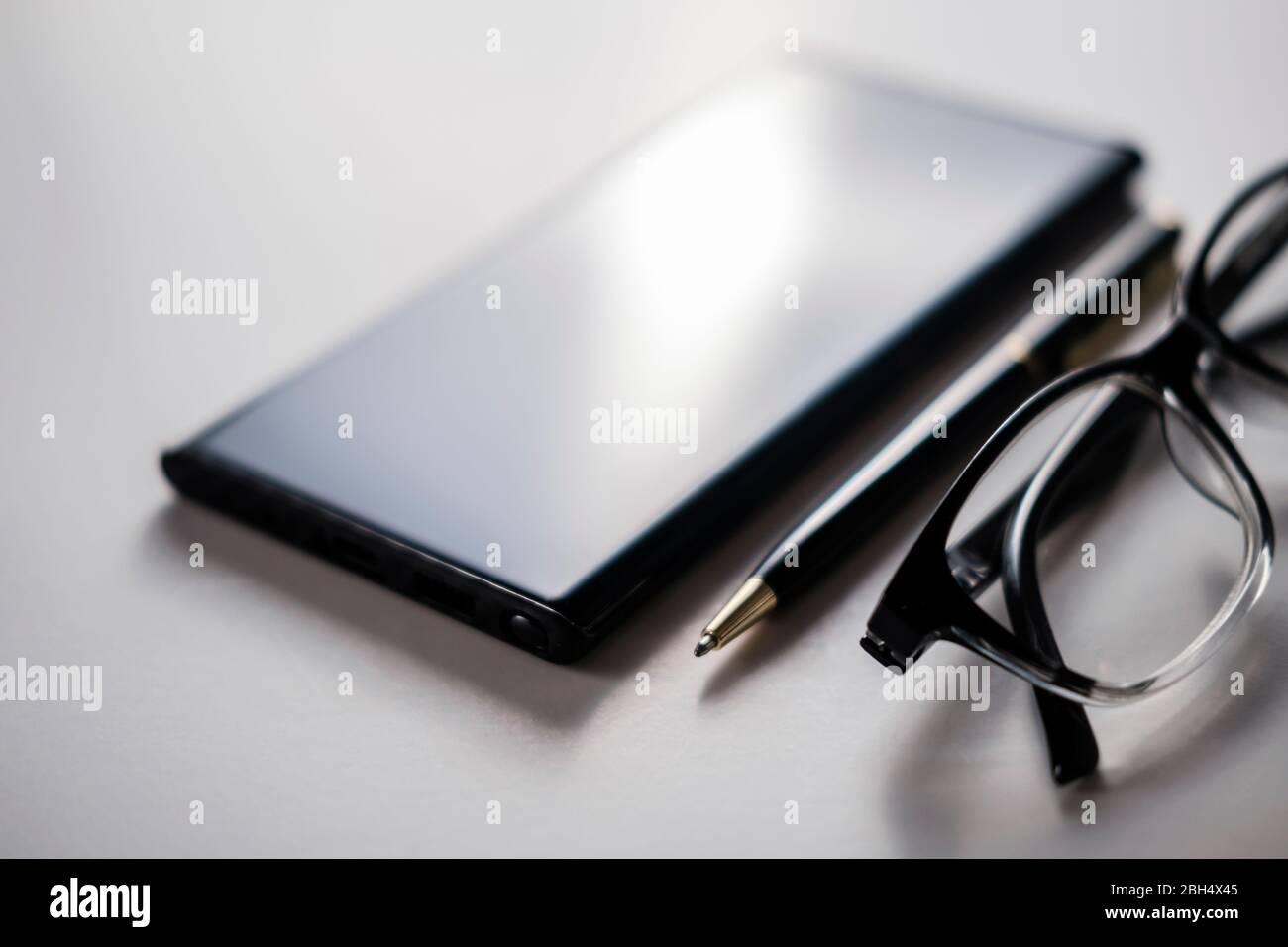 Smartphone, lunettes et stylo Banque D'Images