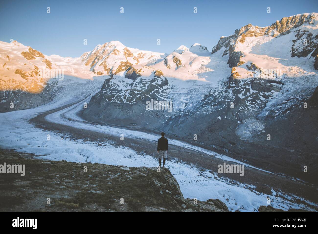 Homme debout sur le rocher par le glacier Gorner en Valais, Suisse Banque D'Images
