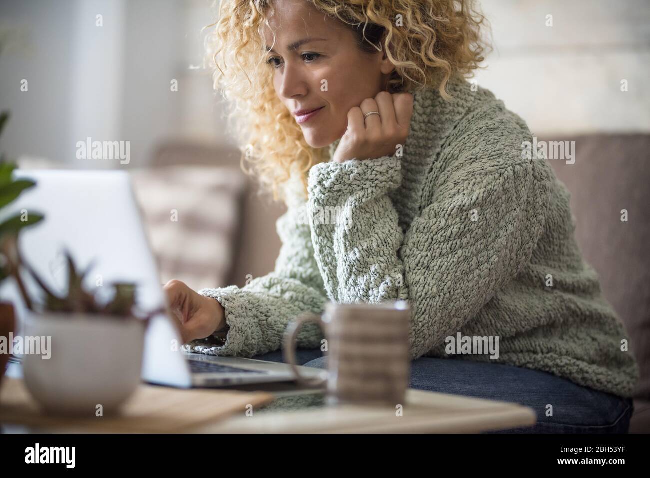 Femme souriante travaillant avec un ordinateur portable sur un canapé Banque D'Images