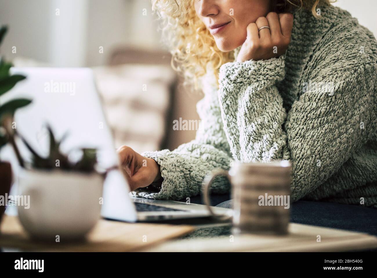 Femme souriante travaillant avec un ordinateur portable sur un canapé Banque D'Images