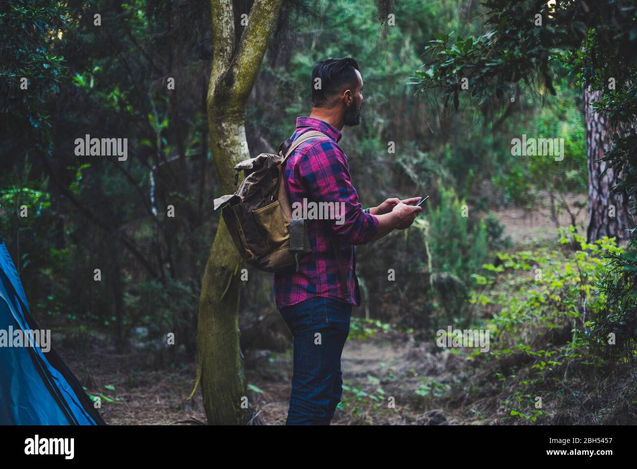 Homme portant un sac à dos avec un smartphone en forêt Banque D'Images