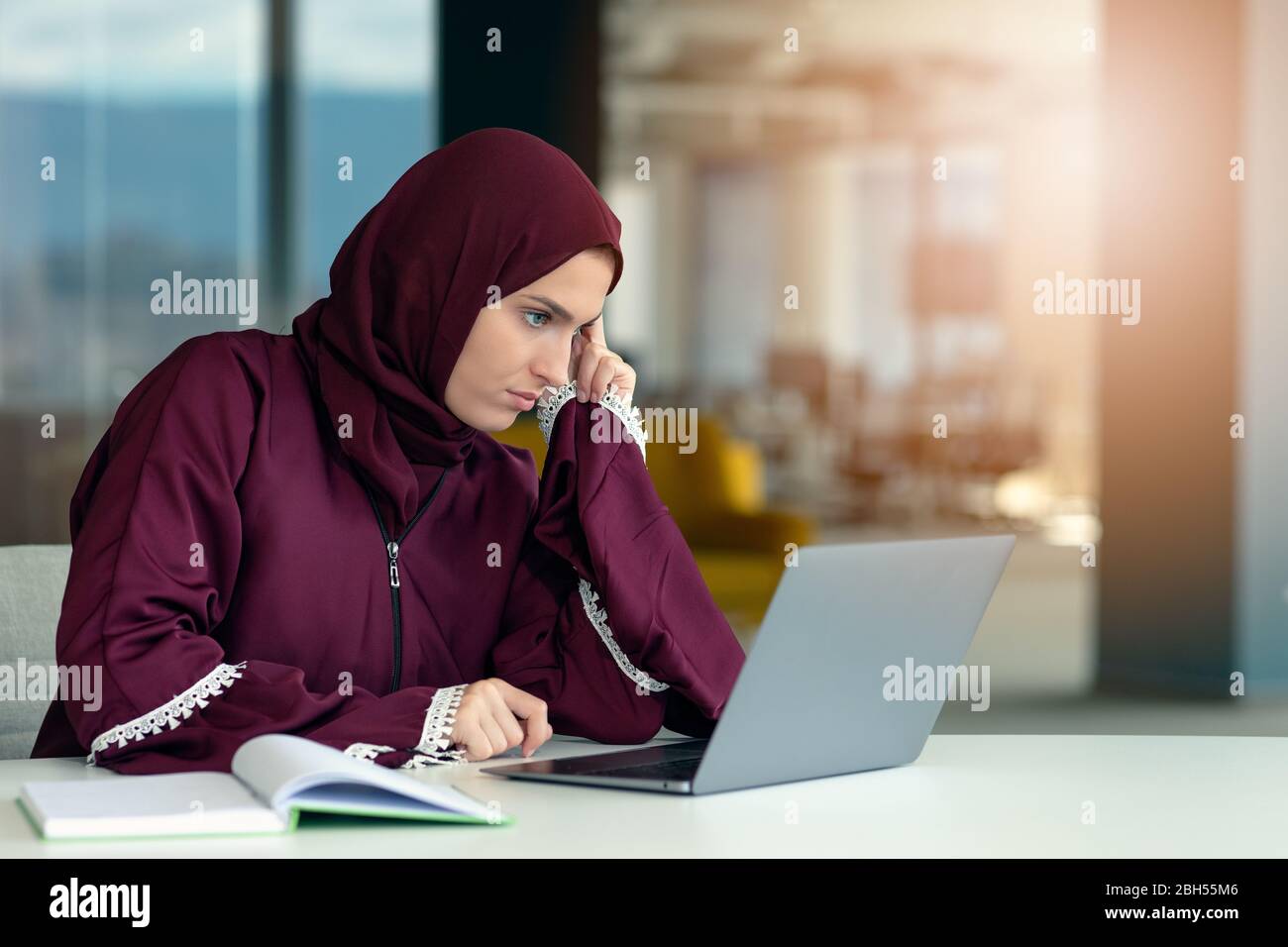 Femme d'affaires arabe pensive assise au bureau Banque D'Images