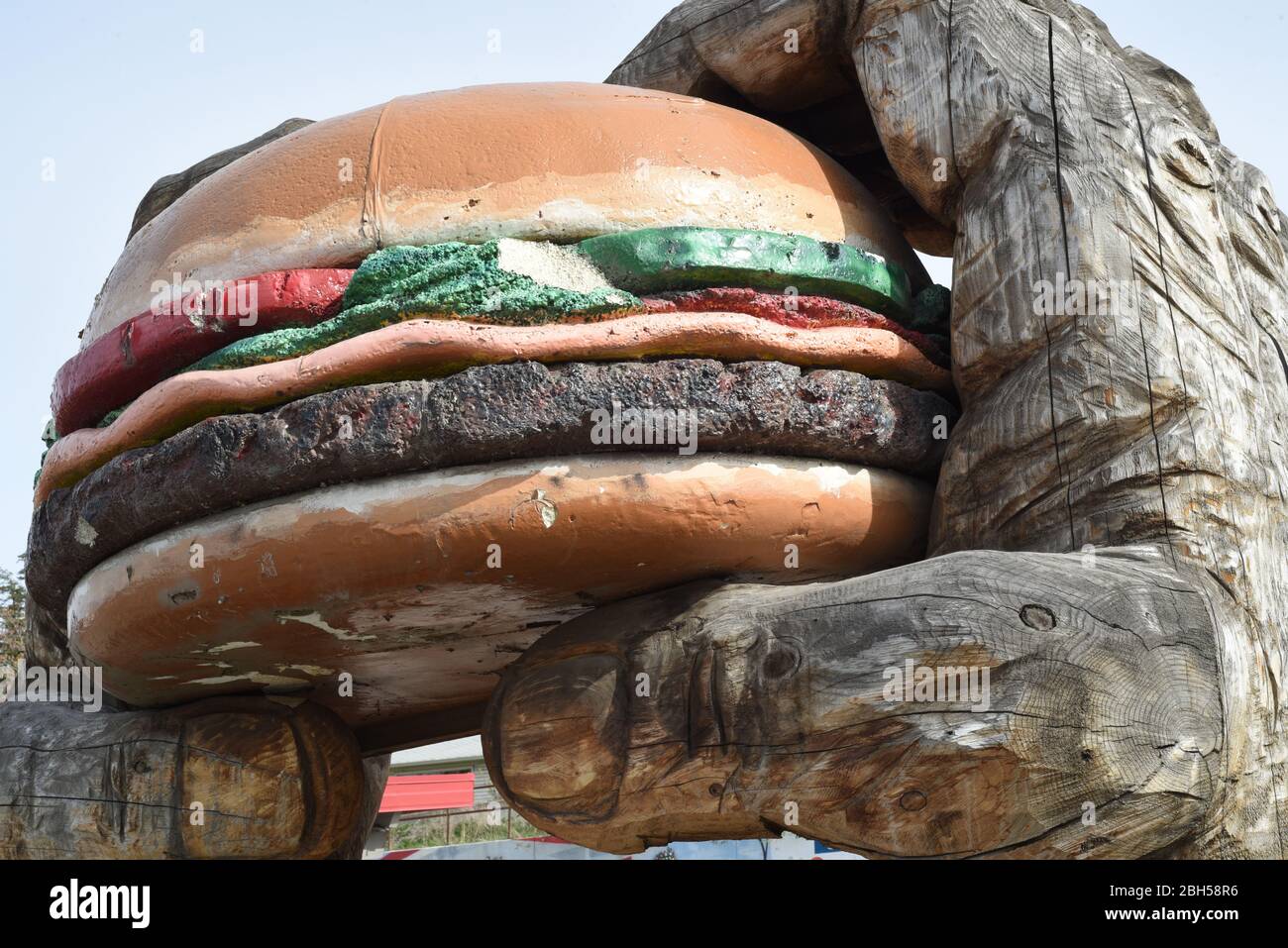 Une paire de mains sculptées géante en bois possède un modèle de hamburger surdimensionné à l'extérieur du restaurant Dog n'Suds de Williams Lake, en Colombie-Britannique, au Canada Banque D'Images