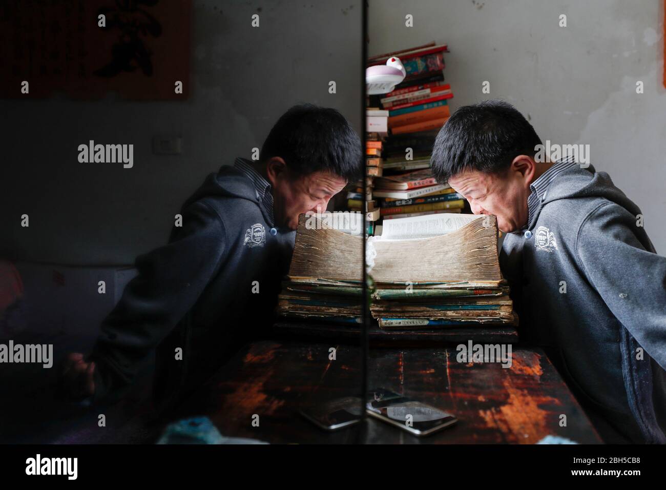 Pékin, la municipalité chinoise de Chongqing. 21 avril 2020. Zhang Yong, qui a la paralysie cérébrale, essaie de tourner les pages avec sa bouche tout en lisant un livre dans le district de Nanchuan, dans le sud-ouest de la municipalité de Chongqing en Chine, le 21 avril 2020. Crédit: Huang Wei/Xinhua/Alay Live News Banque D'Images