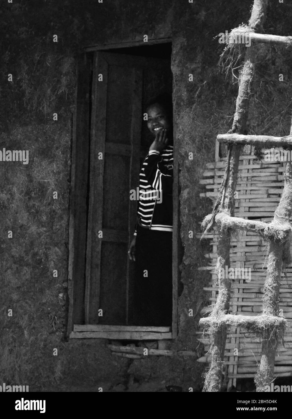 Une femme éthiopienne debout à son porte de maison de village et souriante. Banque D'Images