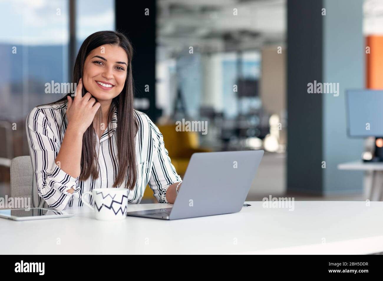 Jeune femme d'affaires souriante au travail dans un bureau moderne. Banque D'Images
