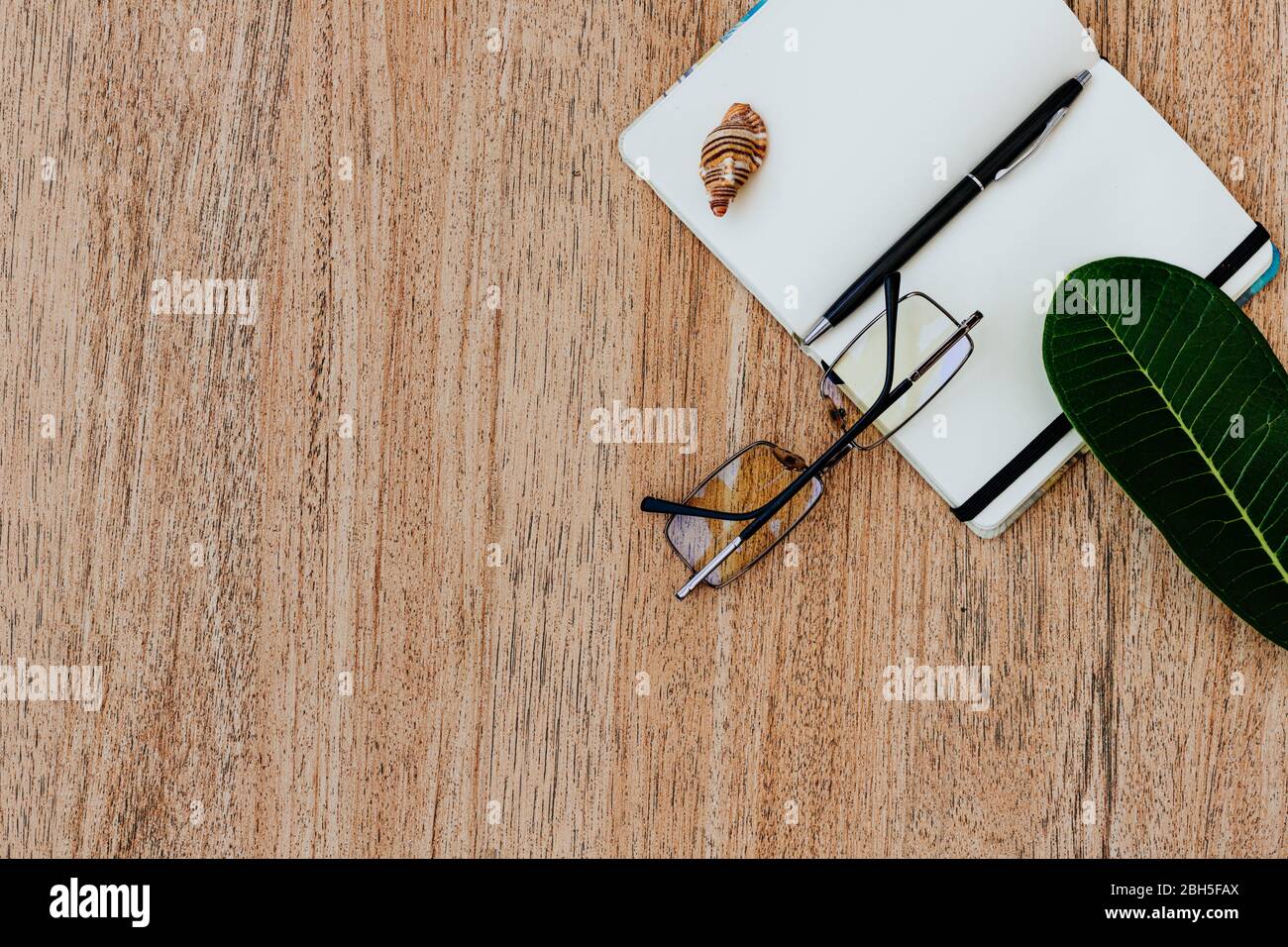 Plat, vue sur le dessus d'un cahier blanc ouvert avec stylo pour écrire des affaires pour la journée sur une table en bois clair. Surface de travail, avec un espace vide pour le texte, Banque D'Images
