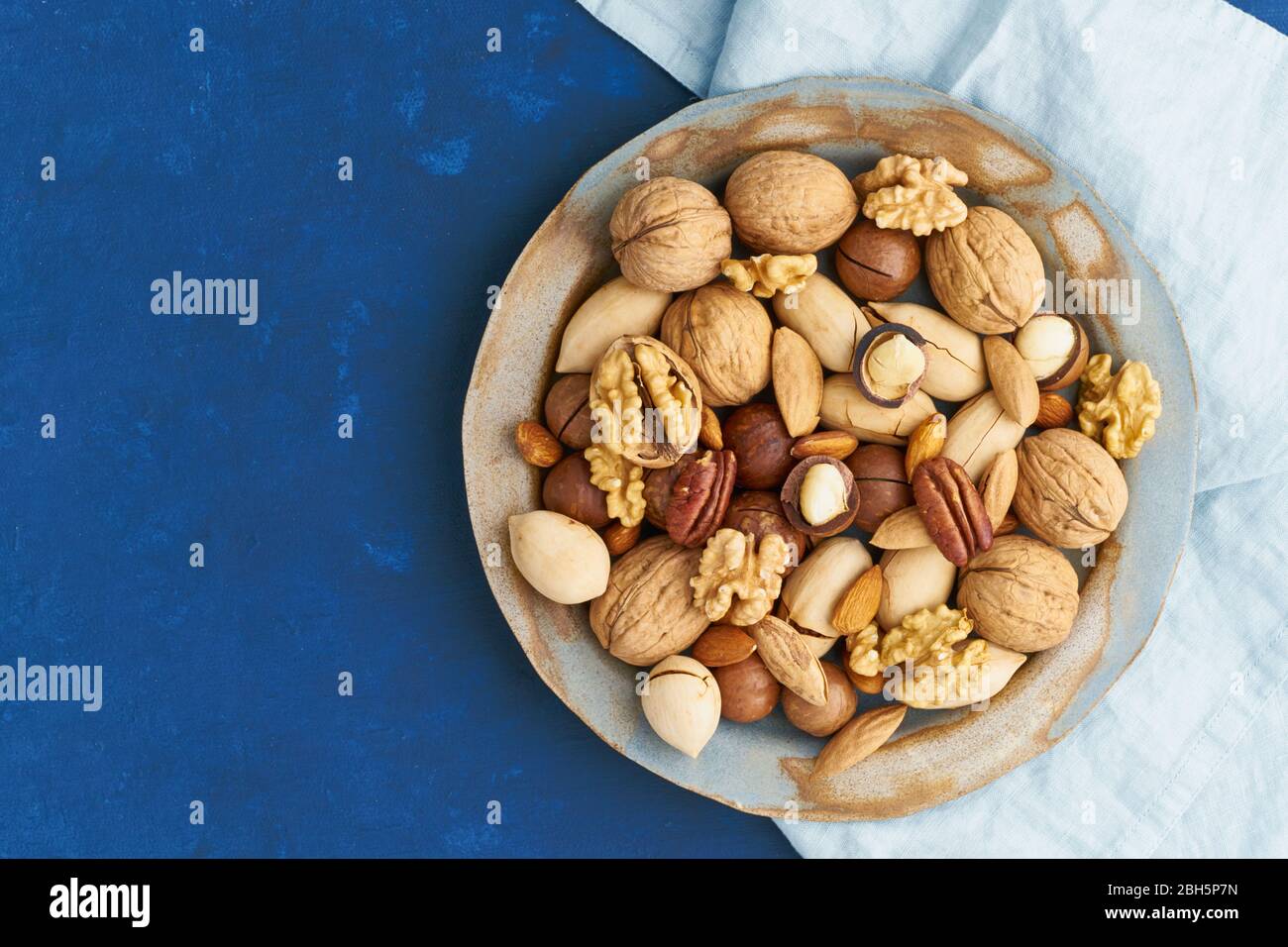 Bleu classique dans la nourriture. Mélange de noix sur plaque - noix, amandes, pacanes, macadamia Banque D'Images