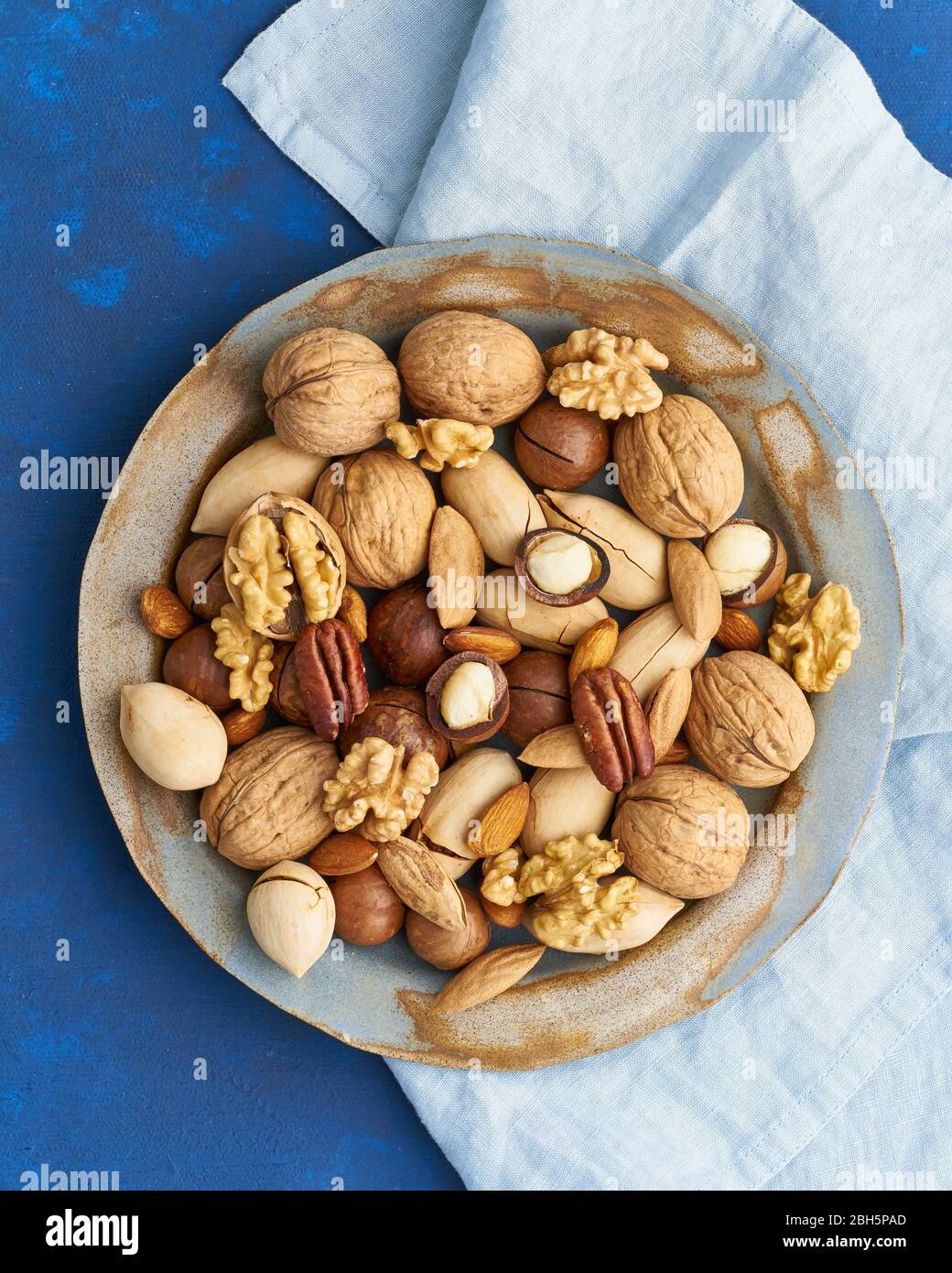 Bleu classique dans la nourriture. Mélange de noix sur plaque - noix, amandes, pacanes, macadamia Banque D'Images