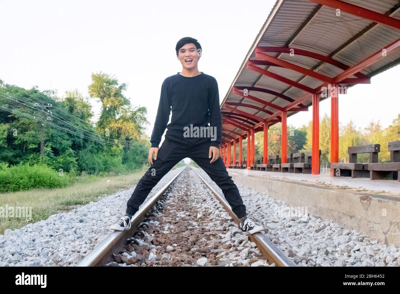 Un garçon est debout sur le chemin de fer à la gare locale. Banque D'Images