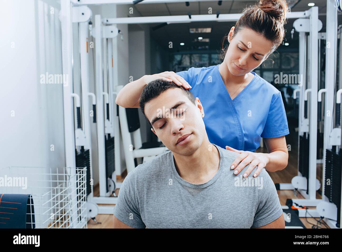 Douleur dans les vertèbres du cou. Le physiothérapeute pétrie le cou d'un homme de course mixte Banque D'Images