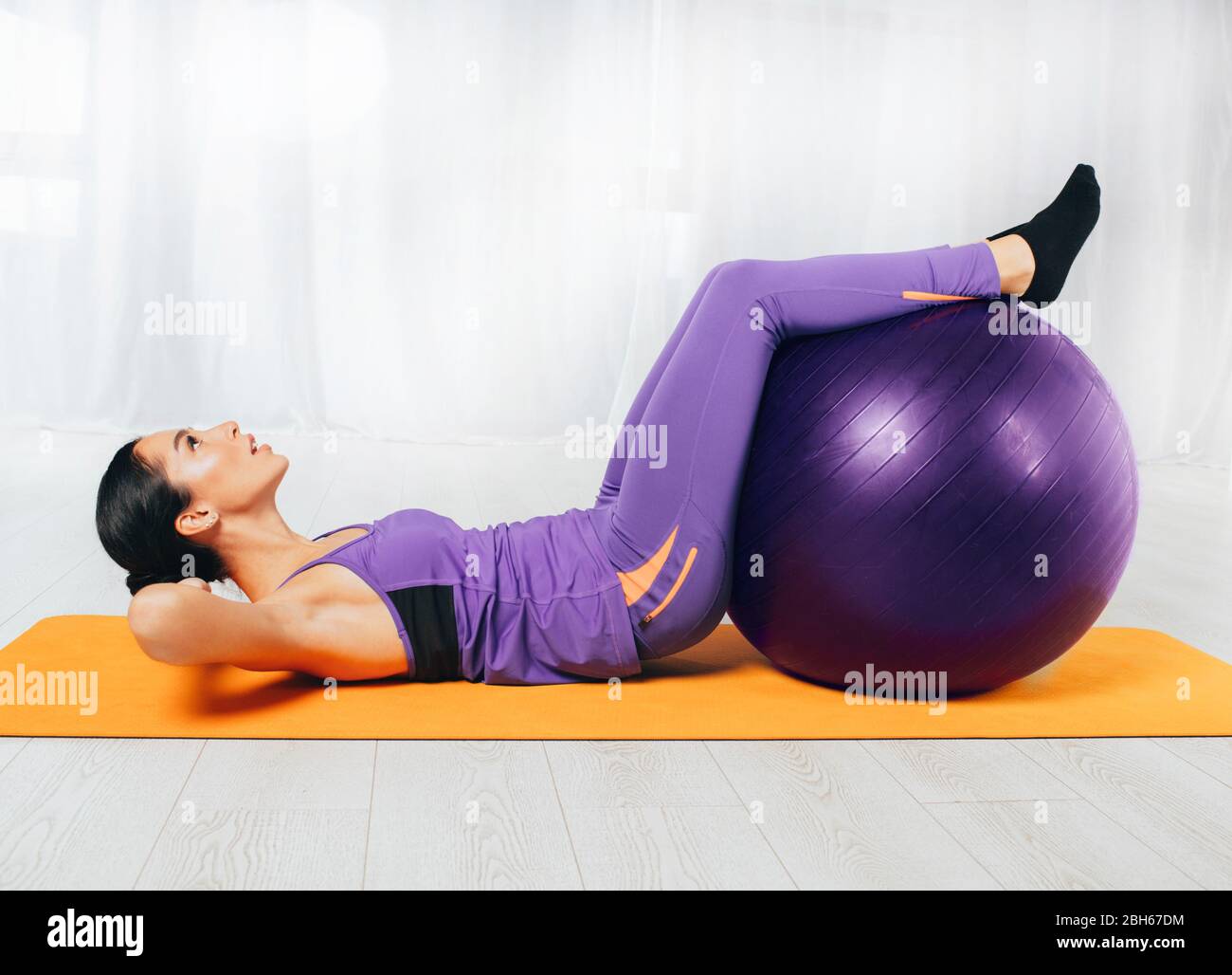 Femme mince entraînement abs avec ballon de fitness au centre de bien-être. Entraînement féminin assez sportif Banque D'Images