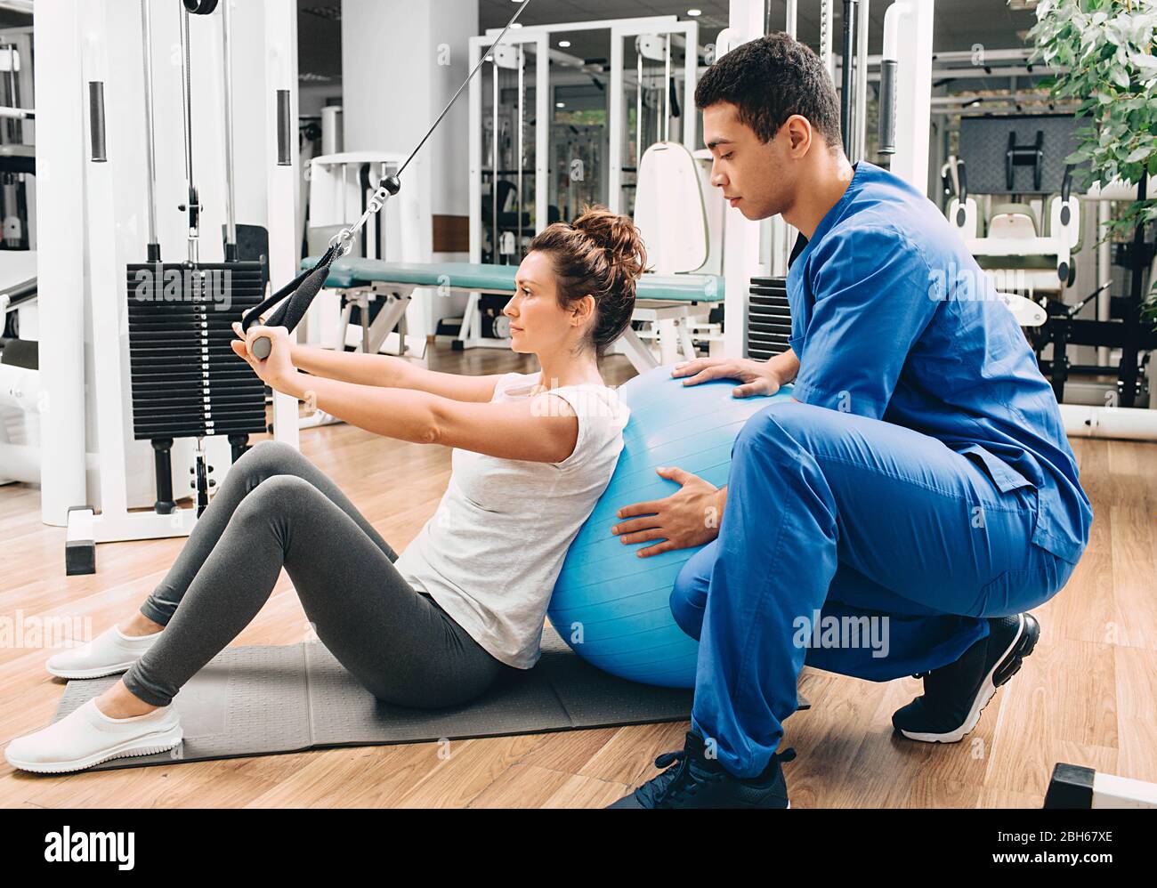 kinésiologue aide une femme à faire des exercices pour renforcer ses muscles du dos. traitement de la douleur du dos avec kinésithérapie. Banque D'Images