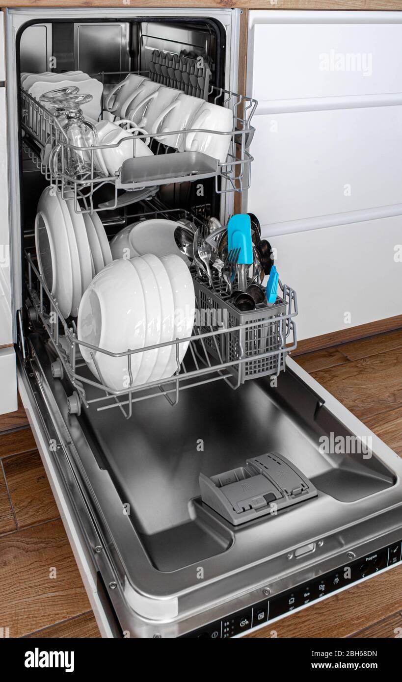 Lave-vaisselle intégré dans une cuisine moderne avec des plats propres après le lavage. Vue latérale Banque D'Images