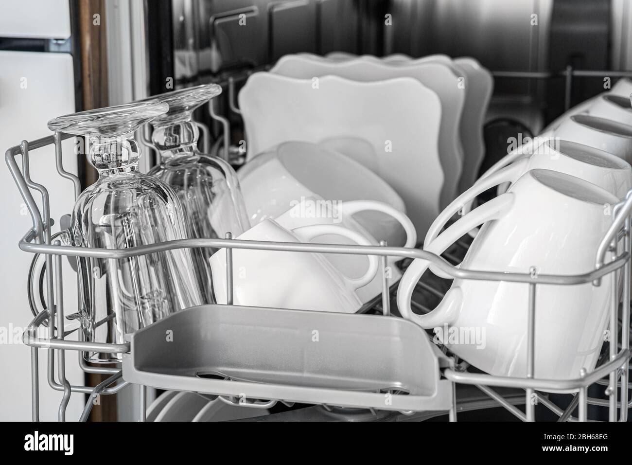 Dans le panier du lave-vaisselle se trouve beaucoup de plats propres. Les tasses et les assiettes brillent après le lavage, le gros plan Banque D'Images
