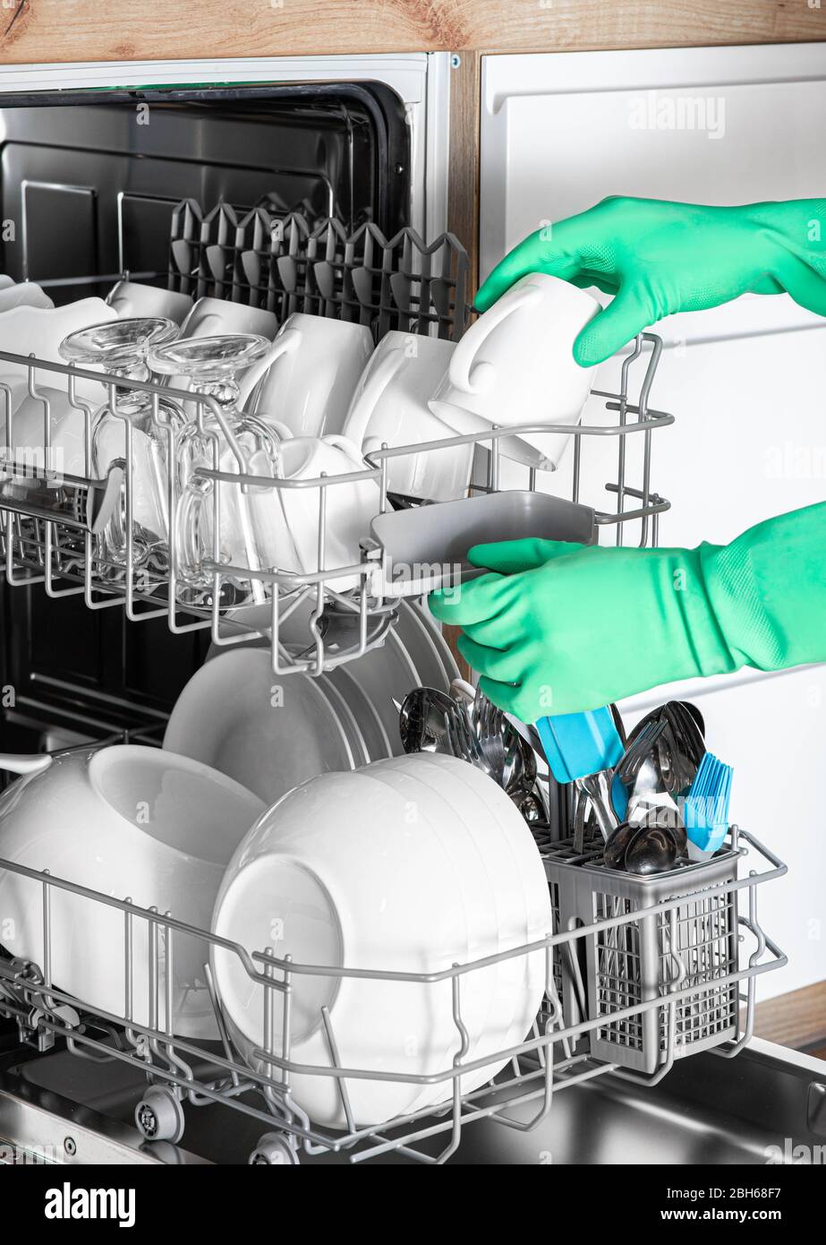 La main féminine courte permet de retirer les plats propres du lave-vaisselle. Vaisselle parfaitement lavée. Lave-vaisselle intégré Banque D'Images