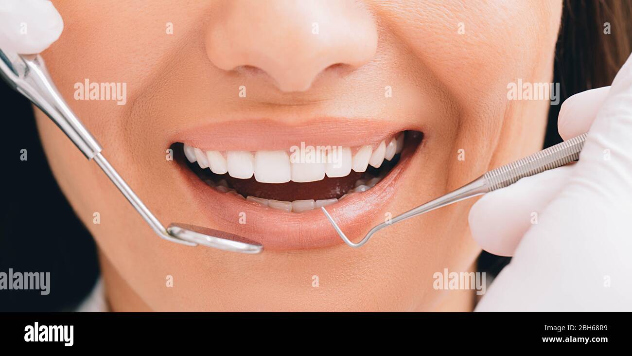 Un sourire parfait court et des mains de dentiste tenant un équipement dentaire et un miroir d'angle. Dentisterie et traitement des dents Banque D'Images