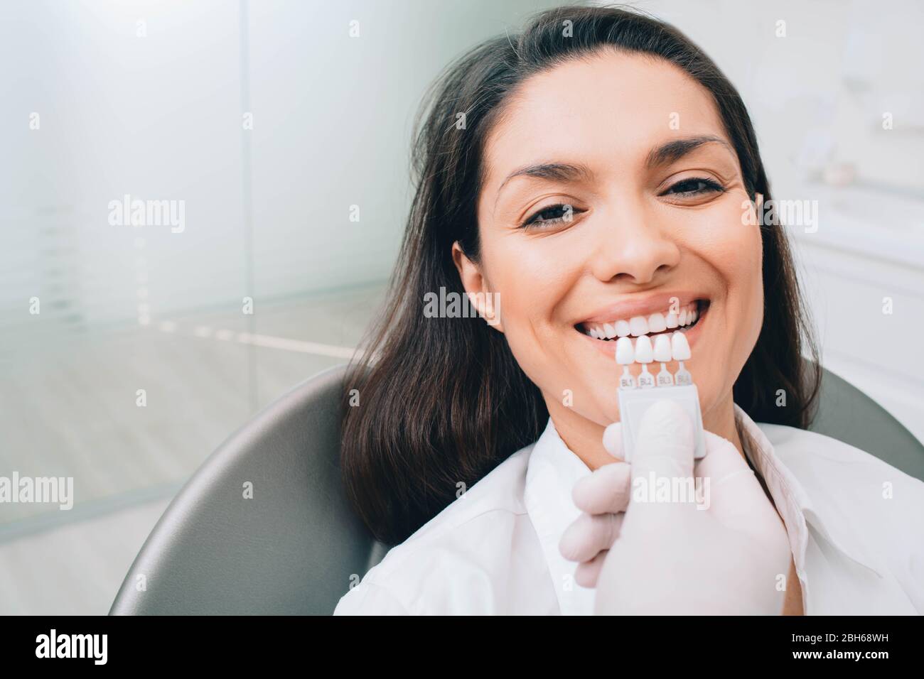 dentiste avec des échantillons de couleur de dents, choisir l'ombre pour les dents de femme à la clinique dentaire. Blanchiment des dents Banque D'Images