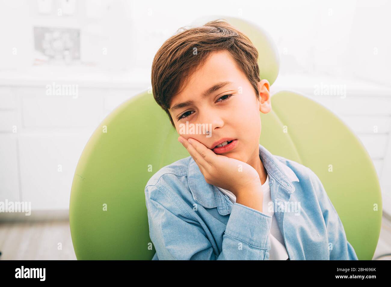 Petit garçon avec douleur de dents, il est triste et bouleversé.il le cadre et le dentiste chaise ad clinique dentaire Banque D'Images