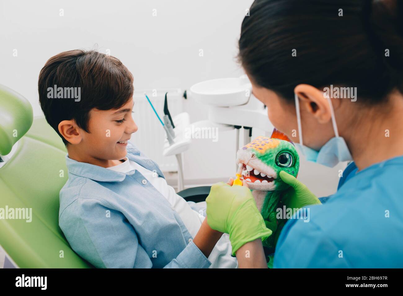Dentiste montrant à un petit garçon comment se brosser correctement les dents. Dentiste montre comment faire l'hygiène dentaire. Banque D'Images