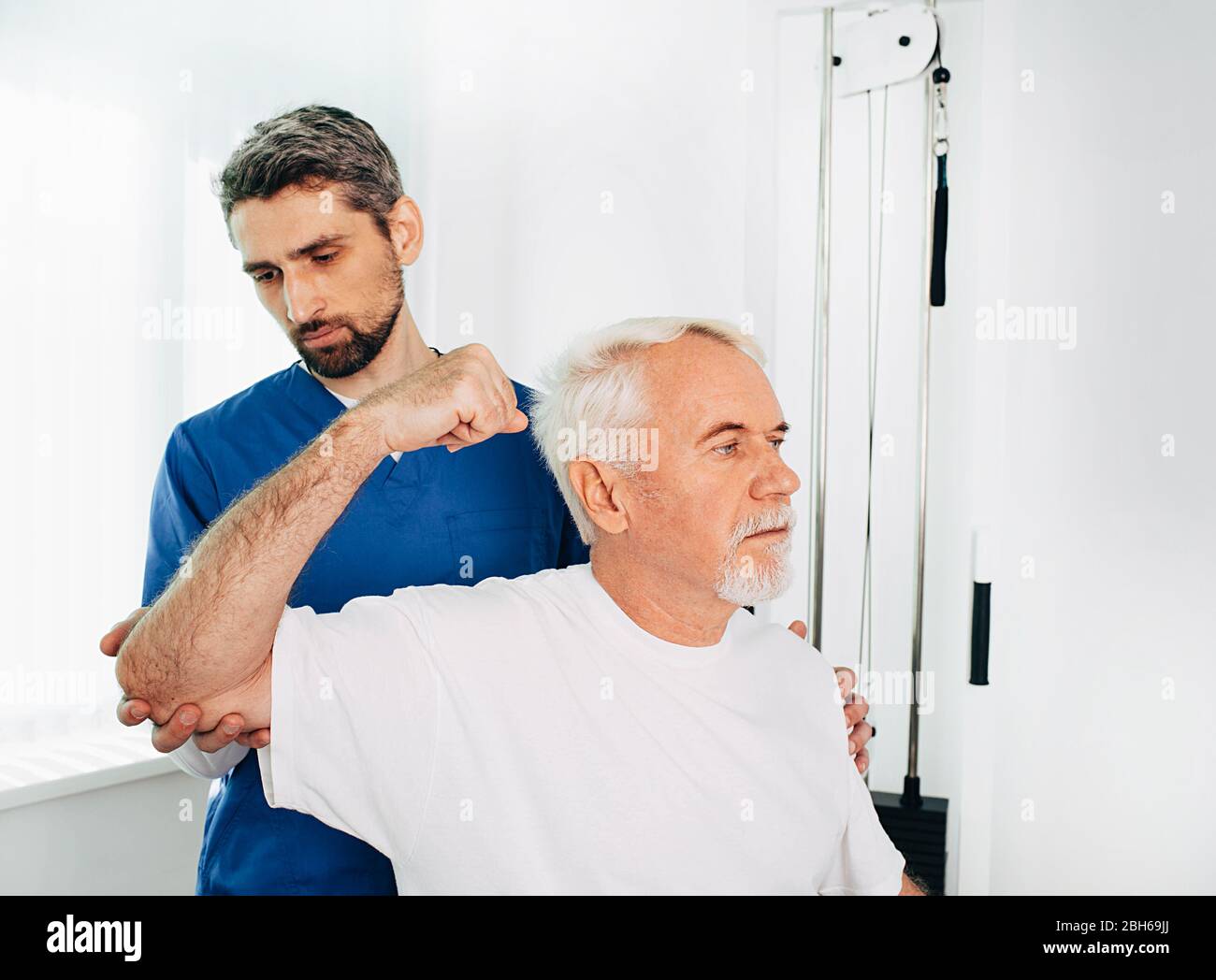 Physiothérapeute masculin aidant un patient âgé dans le rétablissement au centre de réadaptation Banque D'Images