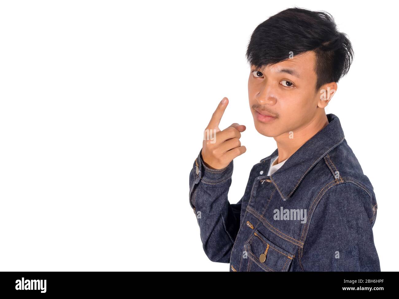 Photo isolée du portrait de vue latérale d'un garçon asiatique dans une veste Jean montrant son doigt de point. Banque D'Images